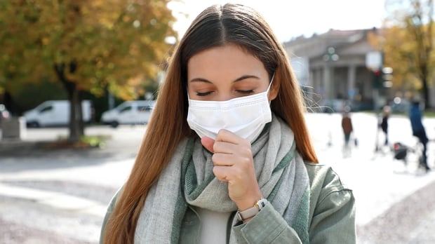  Women with mask outdoors coughing 